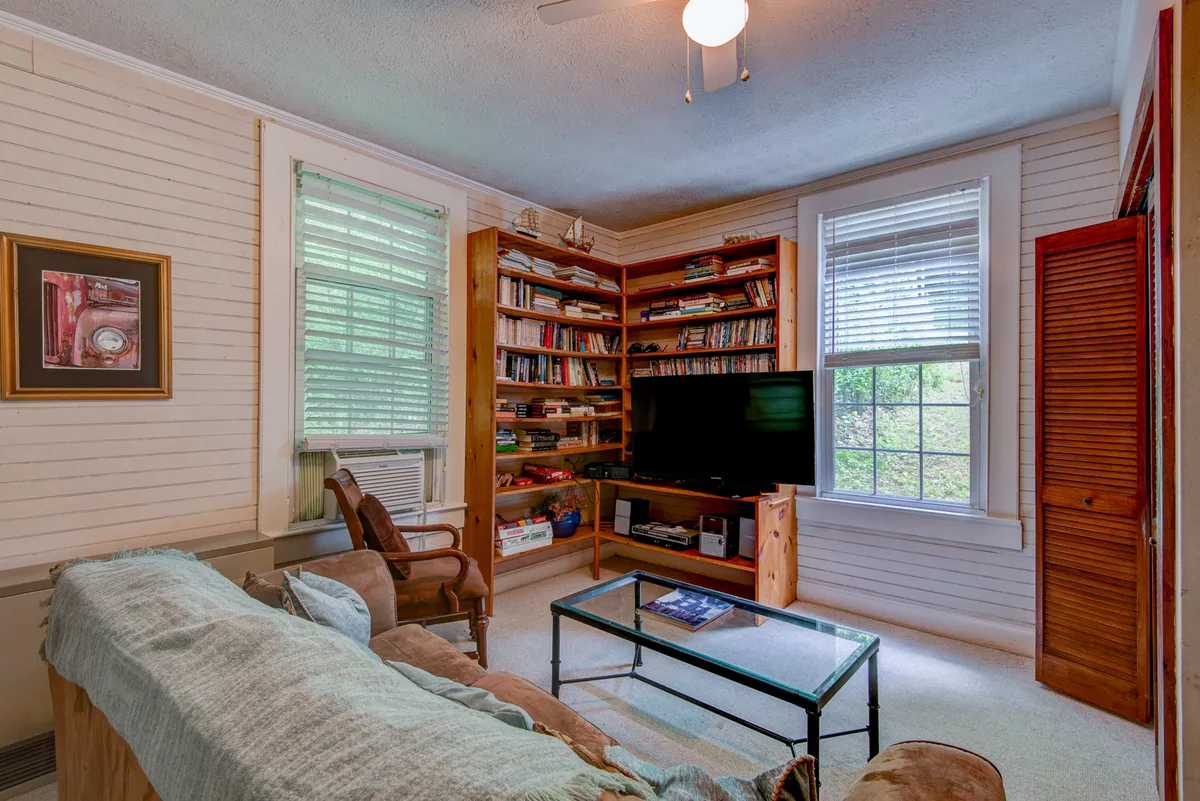 A cozy living room with bookshelves filled with books, a comfortable sofa, and a television. The space is inviting, well-lit, and ideal for curling up with a book or relaxing after a productive work session.