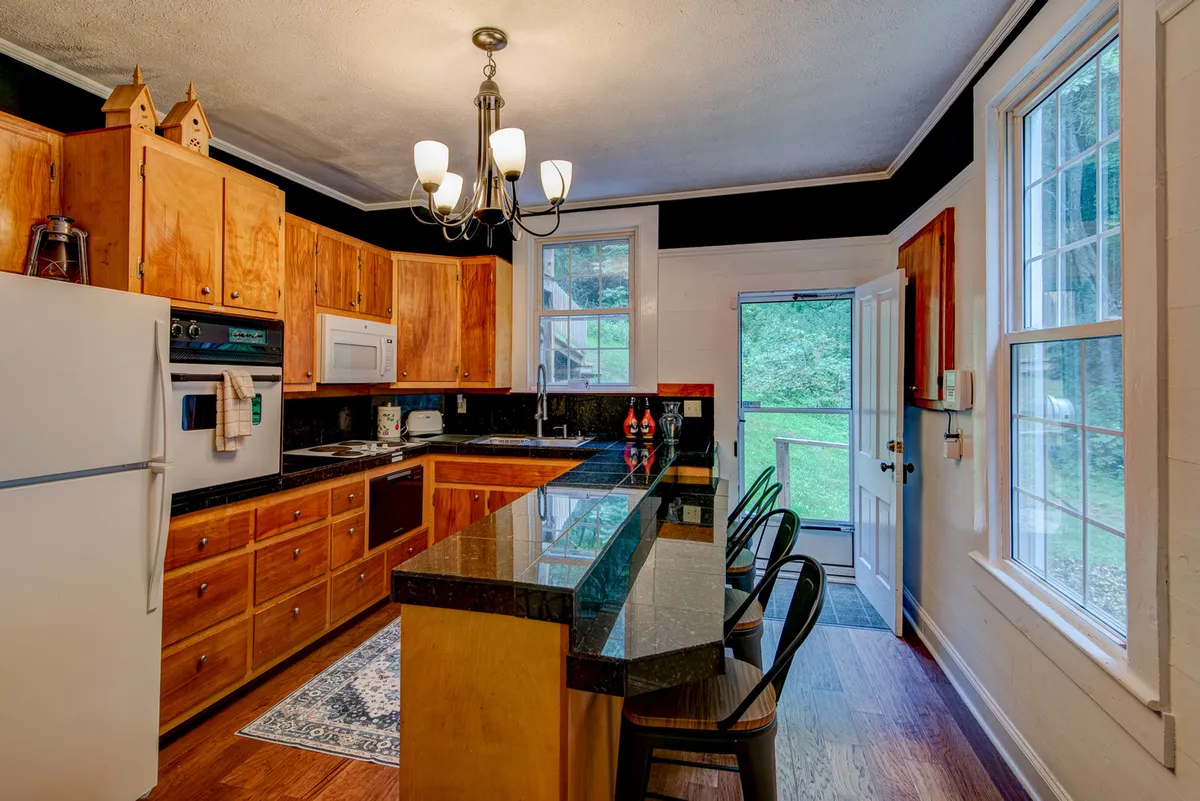 A spacious kitchen featuring a granite countertop, warm wooden cabinetry, a kitchen island perfect for meal prep, and large windows that bathe the room in natural light. The arrangement suggests both ample working space and a welcoming atmosphere for gatherings.