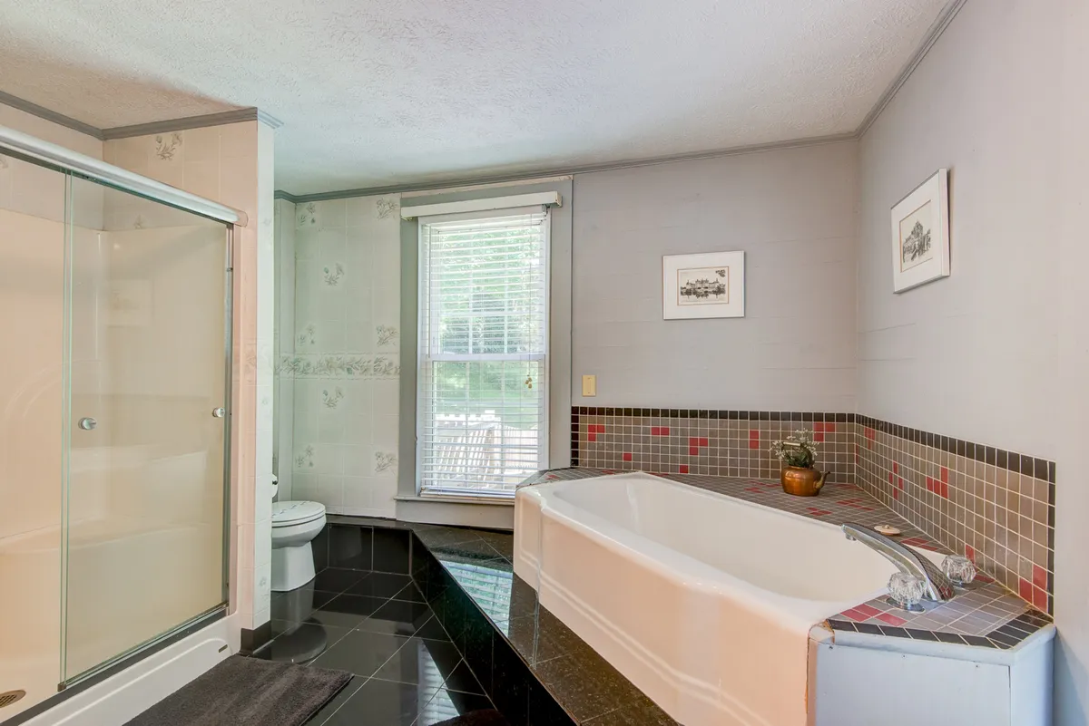 A bright, modern bathroom showcasing a comfortable bathtub, a walk-in shower, a large sink, and a window that bathes the space in natural light. Clean lines and tranquil tones create a spa-like feel.