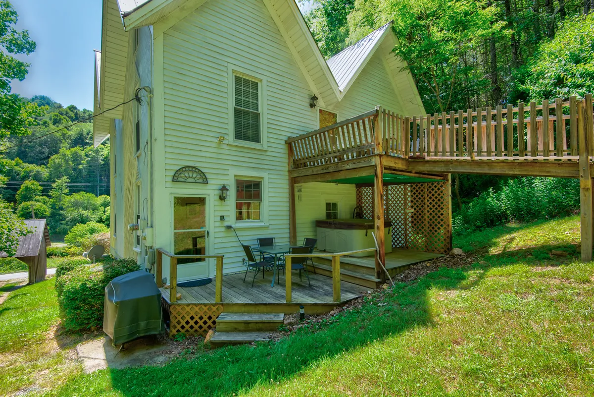 A spacious wooden deck with outdoor seating and a grill, surrounded by lush greenery, invites relaxation and social gatherings. The space overlooks nature, making it ideal for refreshing breaks or enjoying the outdoors between work sessions.