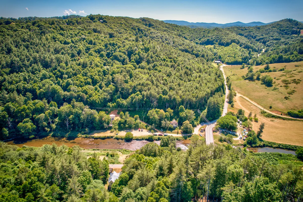 A broad view of a river winding through hills, dotted with scattered homes and a meandering road. Hints of the surrounding terrain and elevation help convey the sense of a remote, scenic location.